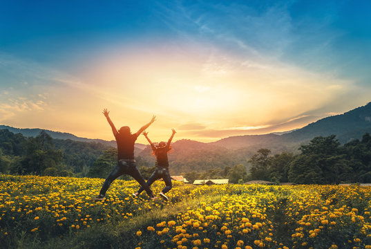 Female love Couples affair with a man standing jumping on a field of yellow flowers. Sunset atmosphere
