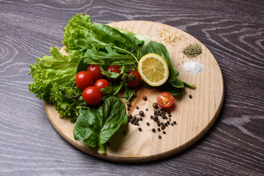 Lettuce, rucola, tomatoes on wooden chopping board