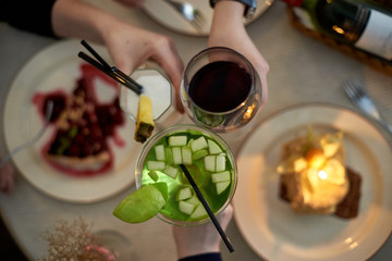 Girls party in cafe. Young woman drinking cocktails and wine and eating cakes. Female hands.