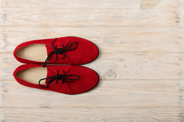 Red women's shoes oxfords on a light wooden background.