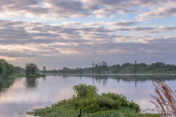 Early morning landscape blue sky with grey and dark clouds against patchy blue water with reflections