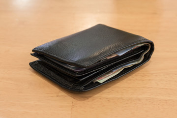 black leather wallet with banknotes for men on Background wood