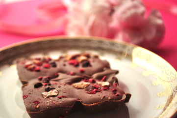 Chocolate on gold and white plate with flowers on bright pink