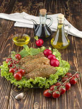 Chicken fillet in marinade with olive oil and olives on a wooden board. 