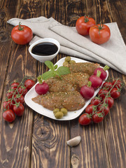 Chicken fillet in marinade with olive oil and olives on a wooden board. 