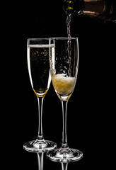 champagne pouring in glass from bottle the evening isolated on black background, close up