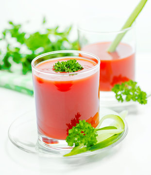tomato juice in transparent glasses with parsley, cucumber and napkin, close up