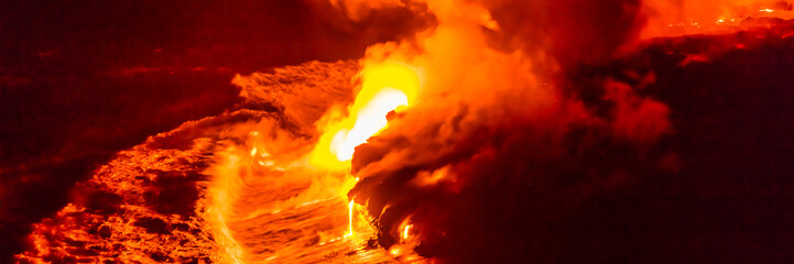 Lava flow falling in ocean waves in Hawaii from Hawaiian Kilauea volcano at night. Molten lava...