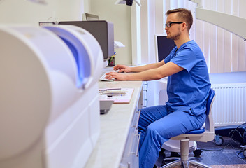 Obraz premium Male dentist in a room with medical equipment on background.