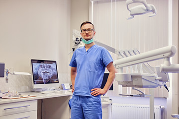 Fototapeta na wymiar Male dentist in a room with medical equipment on background.