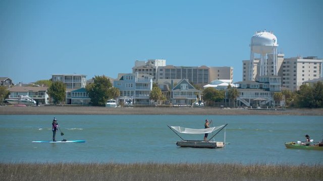 Wilmington NC Outdoor Watersport Activities In Wrightsville Beach With People Enjoying Boating Kayaking And Paddle Boarding With The Landmark Water Tower Background