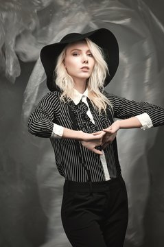 A tall girl dressed in black blouse with white stripes and black pants.