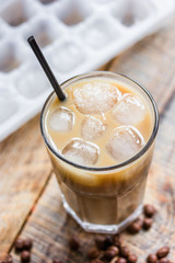 coffee break with cold iced latte and beans on wooden table background