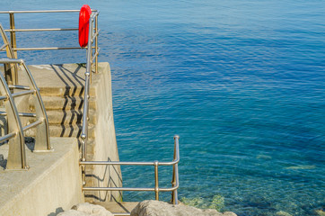 Beautiful blue ocean, part of the promenade with lifebuoy, sunny day