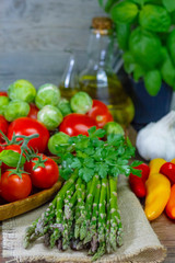 varied vegetables pepper, asparagus, onions, cabbage and olive oil on a wooden background