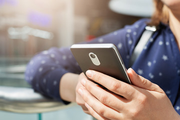 A portrait of elegant woman`s hands using mobile phone reading posts of her friends using free internet connection. A young woman making online shopping using mobile phone