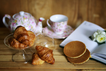 cup with tea croissant book