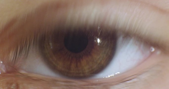 Female green, brown eye close up, macro.4K real time extreme close up shot of the wide open human eye of a female.
