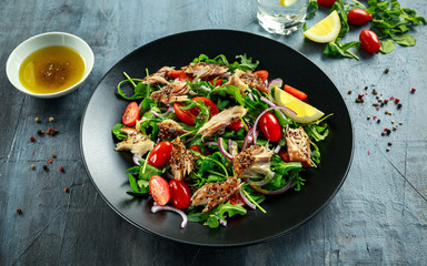 Smoked Mackerel Salad with tomato, chopped red onion, Ruccola on black plate.