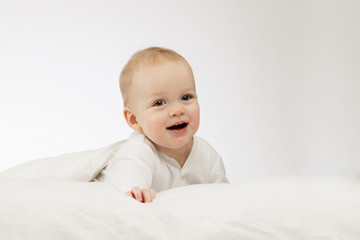 Cute smilling 9 month boy in white bodysuite on white background. Laughing infant kid under blanket. Copy space.