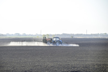The tractor sprayed herbicides on the field. Chemistry in agricu