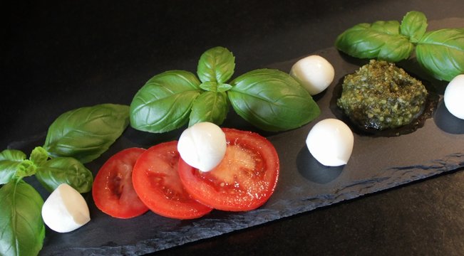 Tomato, mini mozzarella cheese, green pesto and basil leaves