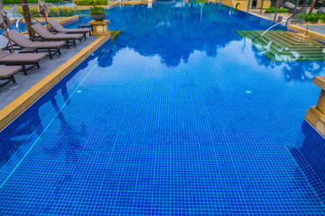 Swimming pool with relaxing seats near the sea .