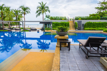 Swimming pool with relaxing seats near the sea .