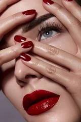 Schönes junges Mädchen im Studio auf grauem Hintergrund. Close-up-Porträt. Frisur-Styling. Glattes, glänzendes Haar und Haut. Rote Lippen, rote Nägel. Schönheit, Körperpflege, Kosmetik. Haltungen. © EkaterinaJurkova