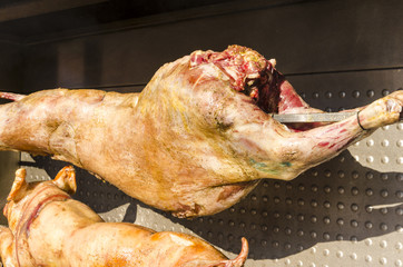 a hot suckling pig and lamb on spit grilled on food market