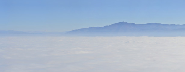 mountain landscape with waves of fog, aerial pov