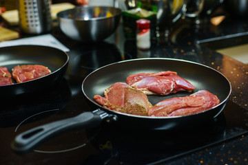 Three large fresh piece of meat in a frying pan.