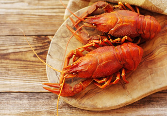 Boiled crayfishes on a wooden board on a wooden background, close up