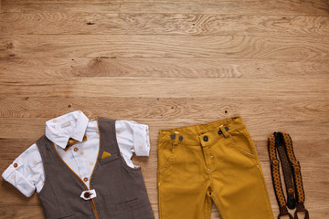 Top view photo of the boy's clothes with accessories on the wooden background.