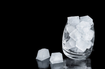 Glass filled with ice cubes, black background.