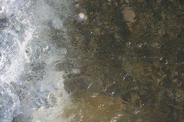 sea pebble beach with multicoloured stones, waves with foam