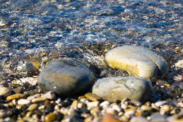 sea pebble beach with multicoloured stones, waves with foam