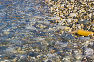 sea pebble beach with multicoloured stones, waves with foam