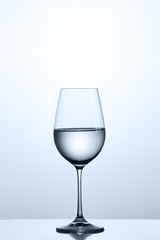 Cleaner water in the fixed wineglass while standing on the clean glass against light background.