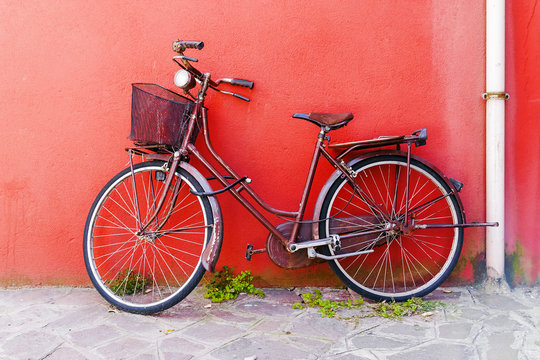 Old bicycle on a red wall background - Powered by Adobe