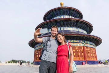 Papier Peint photo autocollant Lieux asiatiques Happy couple travelers taking selfie picture together at temple of heaven during china summer travel. Young multiracial people using phone photography app for photos.