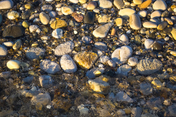 sea pebble beach with multicoloured stones, waves with foam