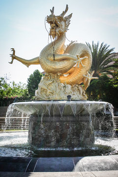 Golden dragen statue in a garden or park.