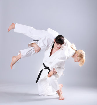 Young sporty women practicing martial arts on light background