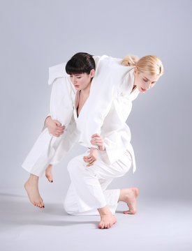 Young sporty women practicing martial arts on light background