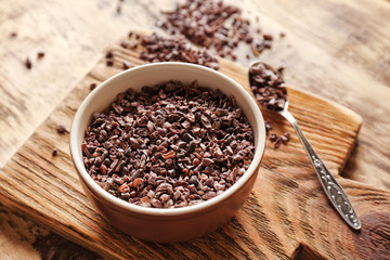 Bowl with aromatic cocoa nibs on wooden table