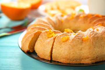 Plate with sliced citrus cake on blue wooden table