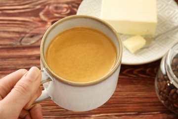 Female hand with cup of tasty butter coffee, closeup