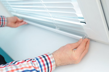 Man installing window blinds at home, close up