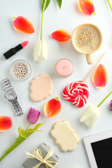 Composition of flowers, sweets, cosmetics and accessories on white table